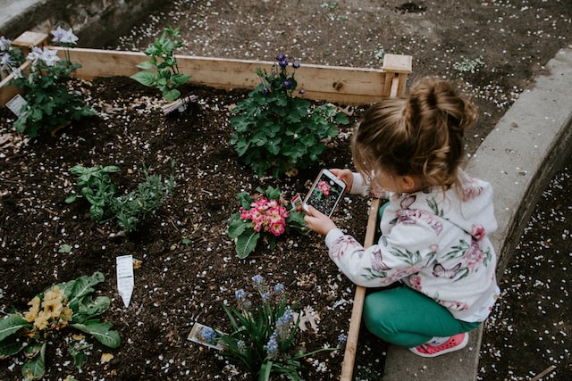 Girl sitting making photo of a flower